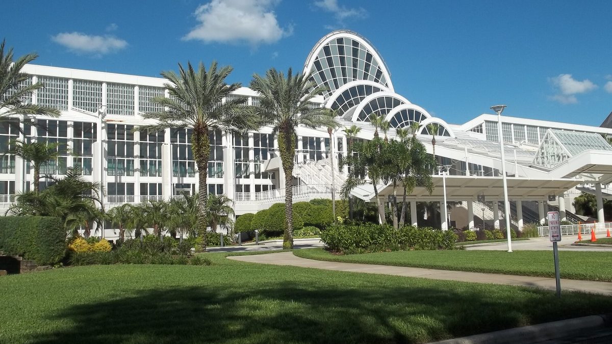 The arched glass roof of the Orange County Convention Center in Orlando, behind palm trees